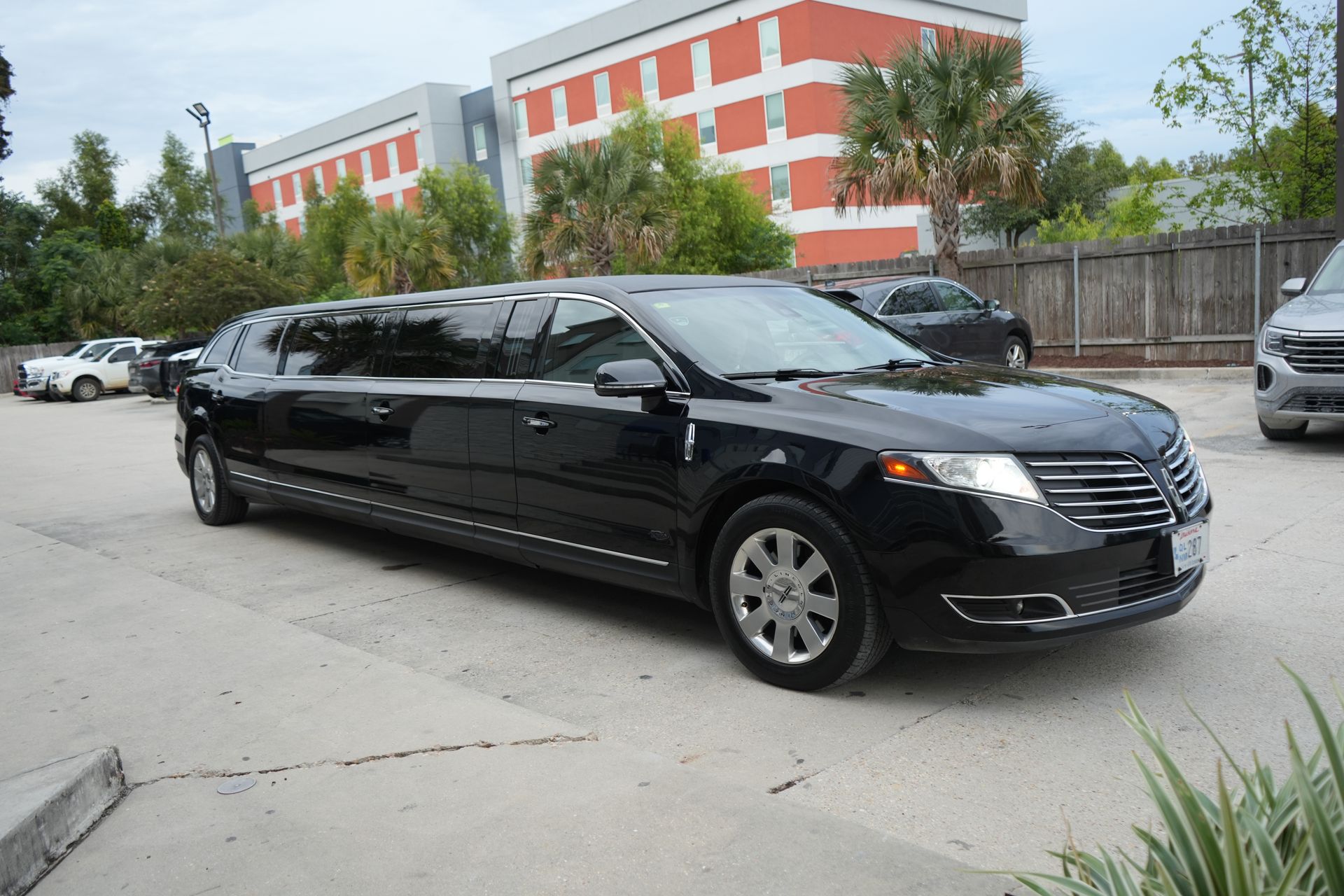 A black limousine is parked in a parking lot in front of a building.