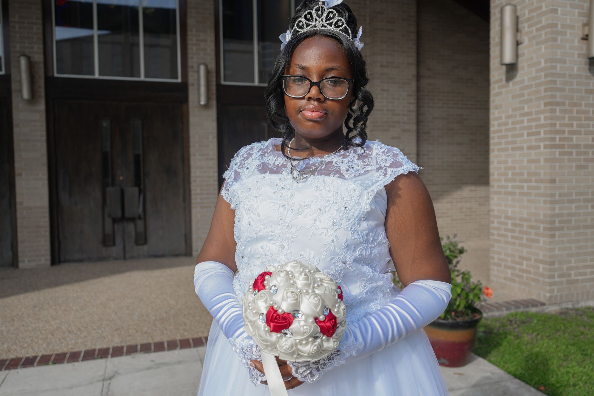 A woman in a white dress and gloves is holding a bouquet of flowers.