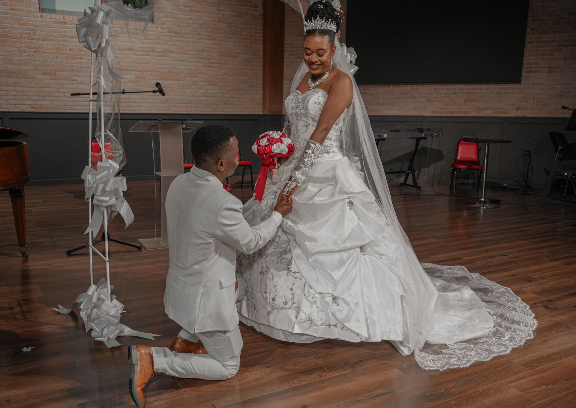 A man is kneeling down next to a bride in a wedding dress.