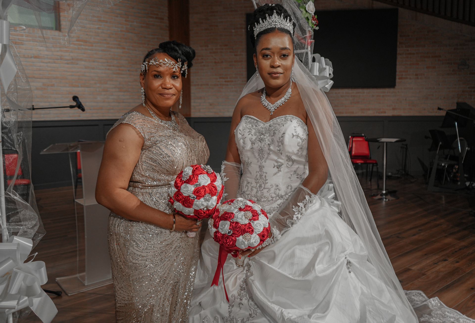Two women in wedding dresses are standing next to each other holding bouquets of flowers.