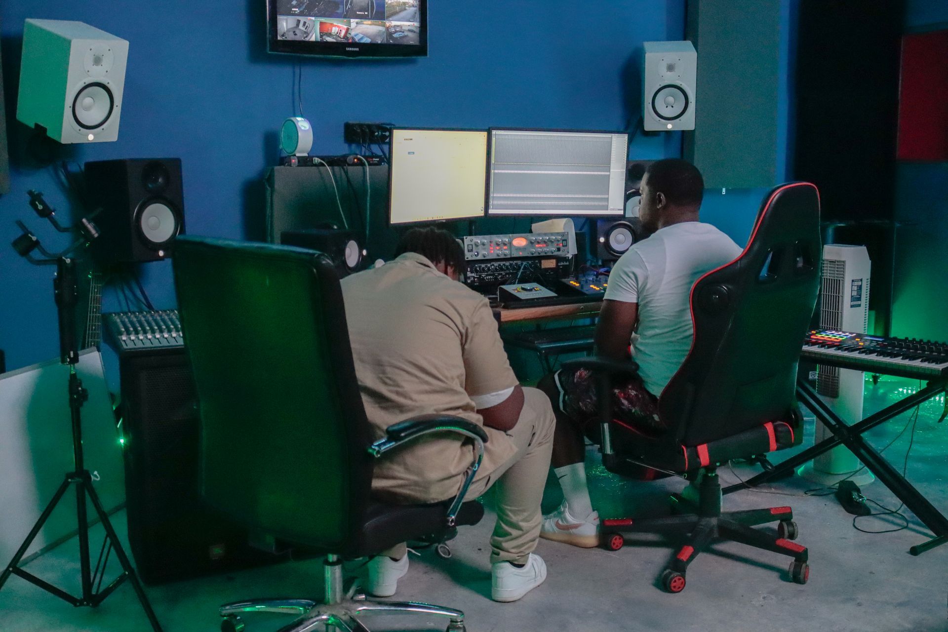 Two men are sitting at a desk in a recording studio.