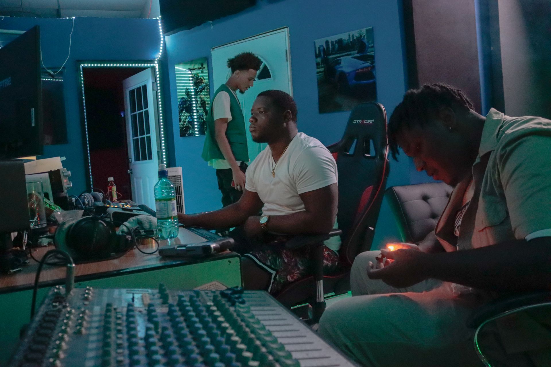 Two men are sitting in front of a mixer in a room.