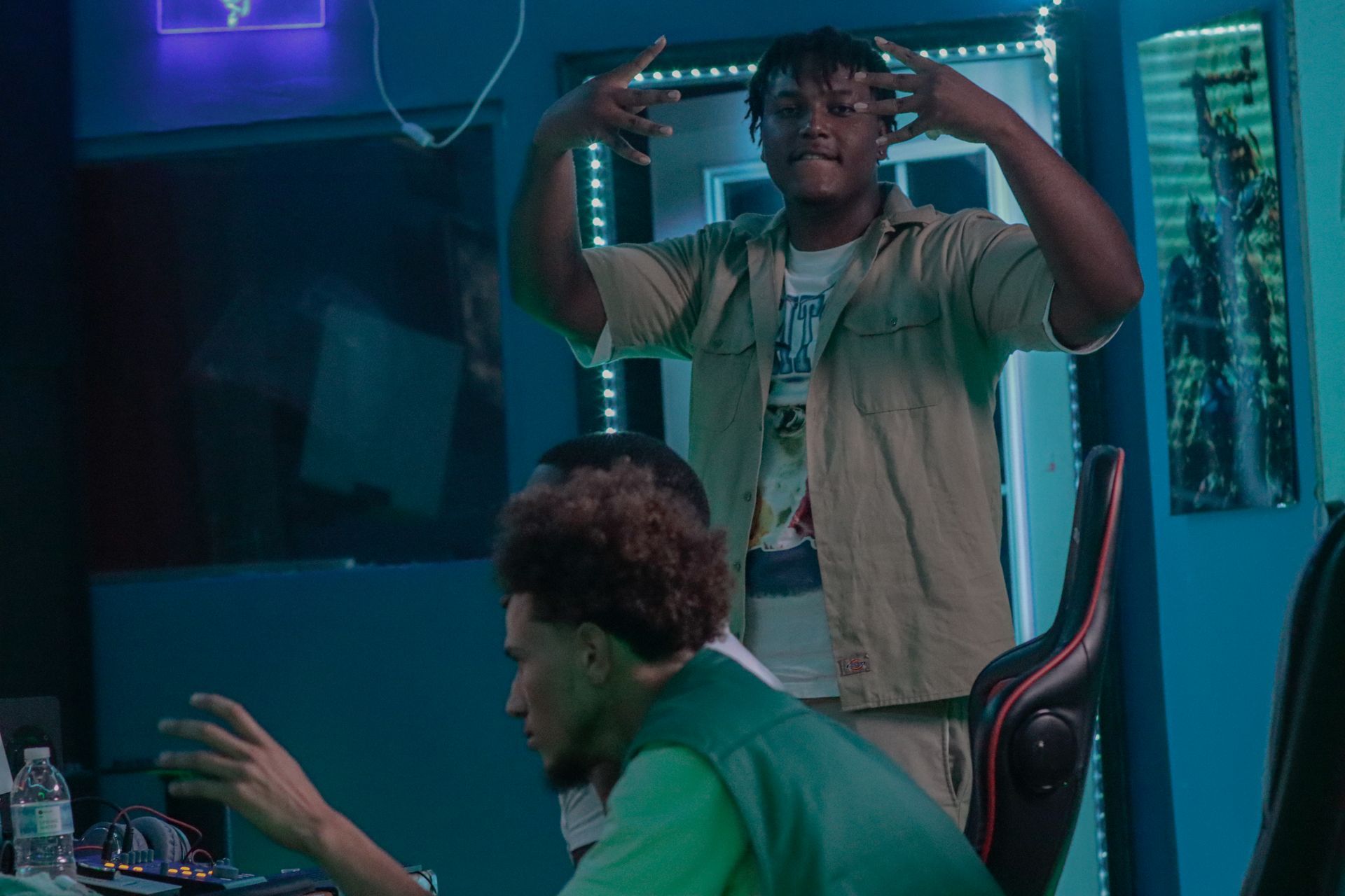 A man is standing next to a man sitting in a chair in a room.