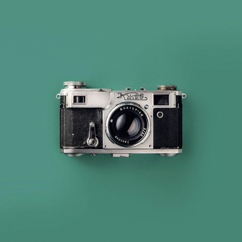 An old camera is sitting on a green surface.