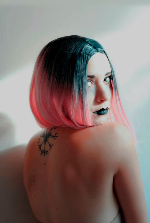 A woman with pink hair and a tattoo on her back.
