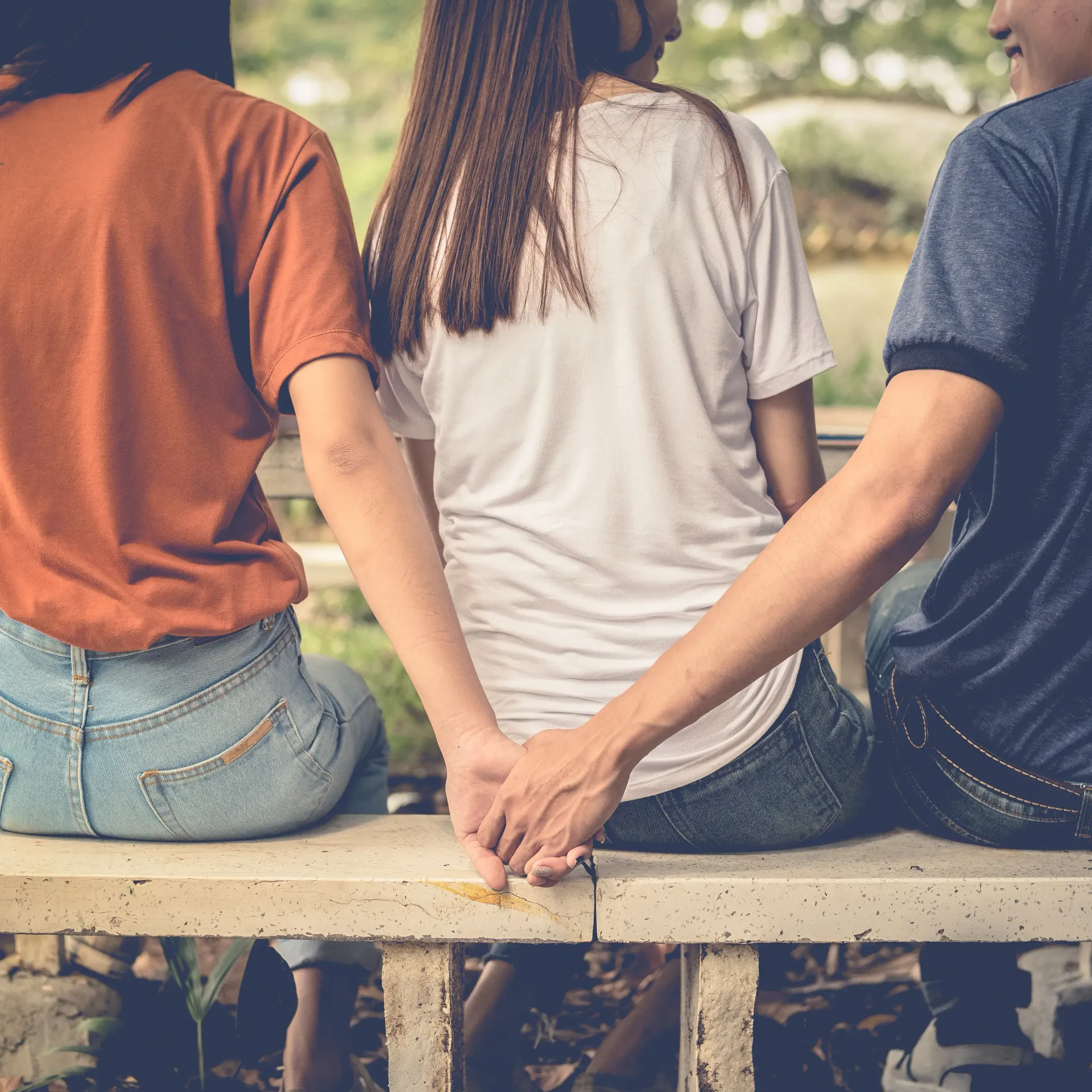 Un hombre sostiene la mano de una mujer mientras está sentado en un banco.