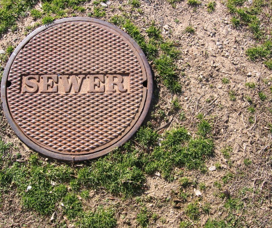 A collapsed sewer line manhole cover with the word sewer on it.