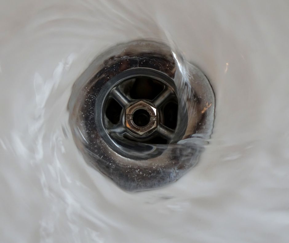 Water swirling down a sink drain, showing how trapped air can cause gurgling plumbing noises.