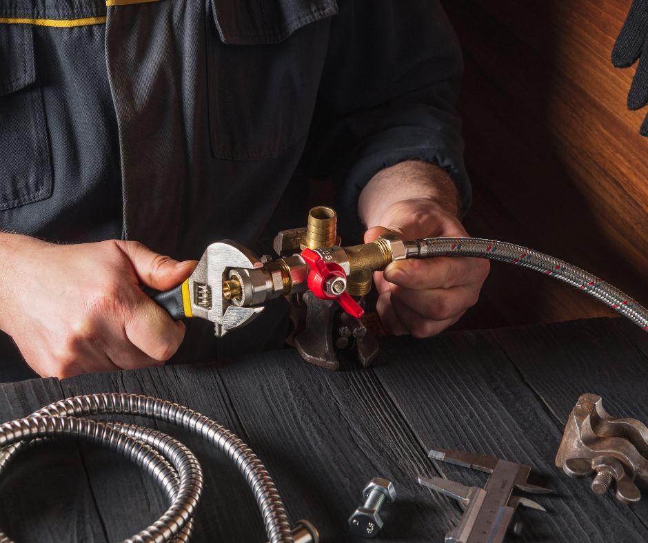 A plumber holding plumbing pipes and fittings, and tightening them up using a pipe wrench