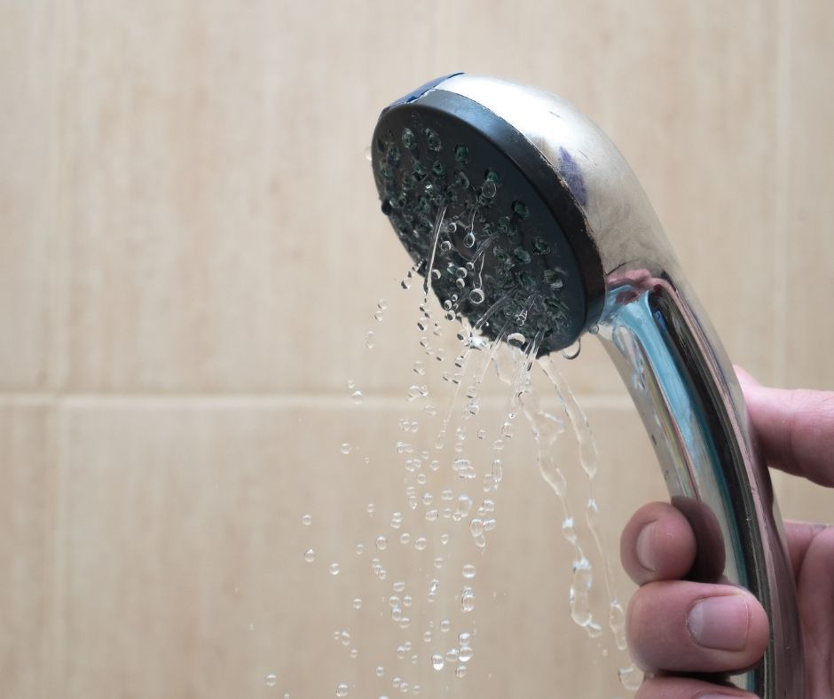 Weak water flow from a showerhead, showing a common sign of low water pressure in the shower.