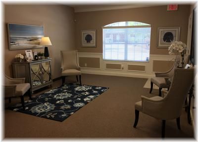 Calm memorial gathering room with upholstered chairs, decorative rug, framed artwork, and natural window light