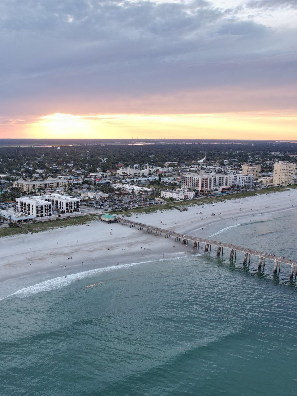 A pier in the middle of the ocean at sunset.
