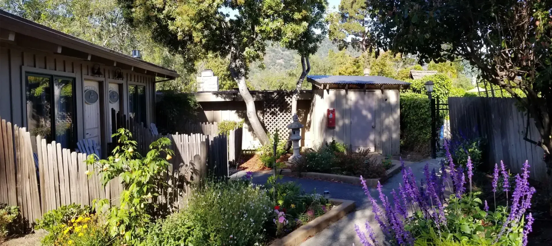 A house with a fence and flowers in front of it.