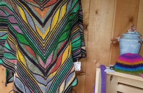 A colorful shawl is hanging on a wooden wall.