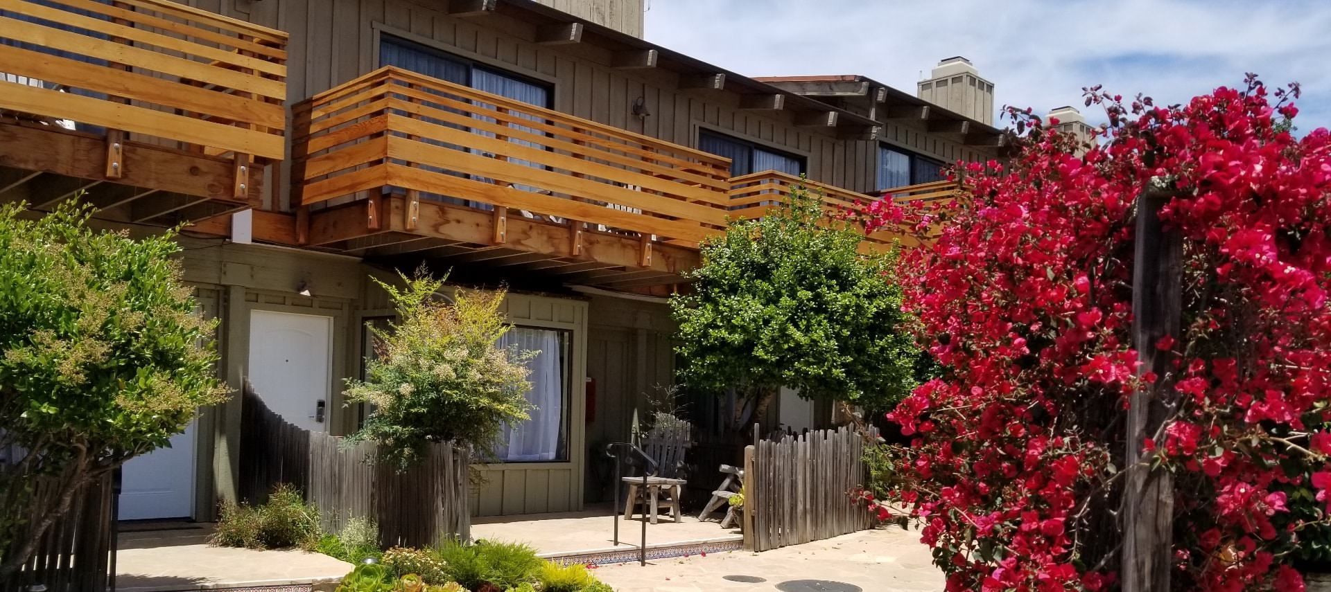 A house with a wooden deck and red flowers in front of it