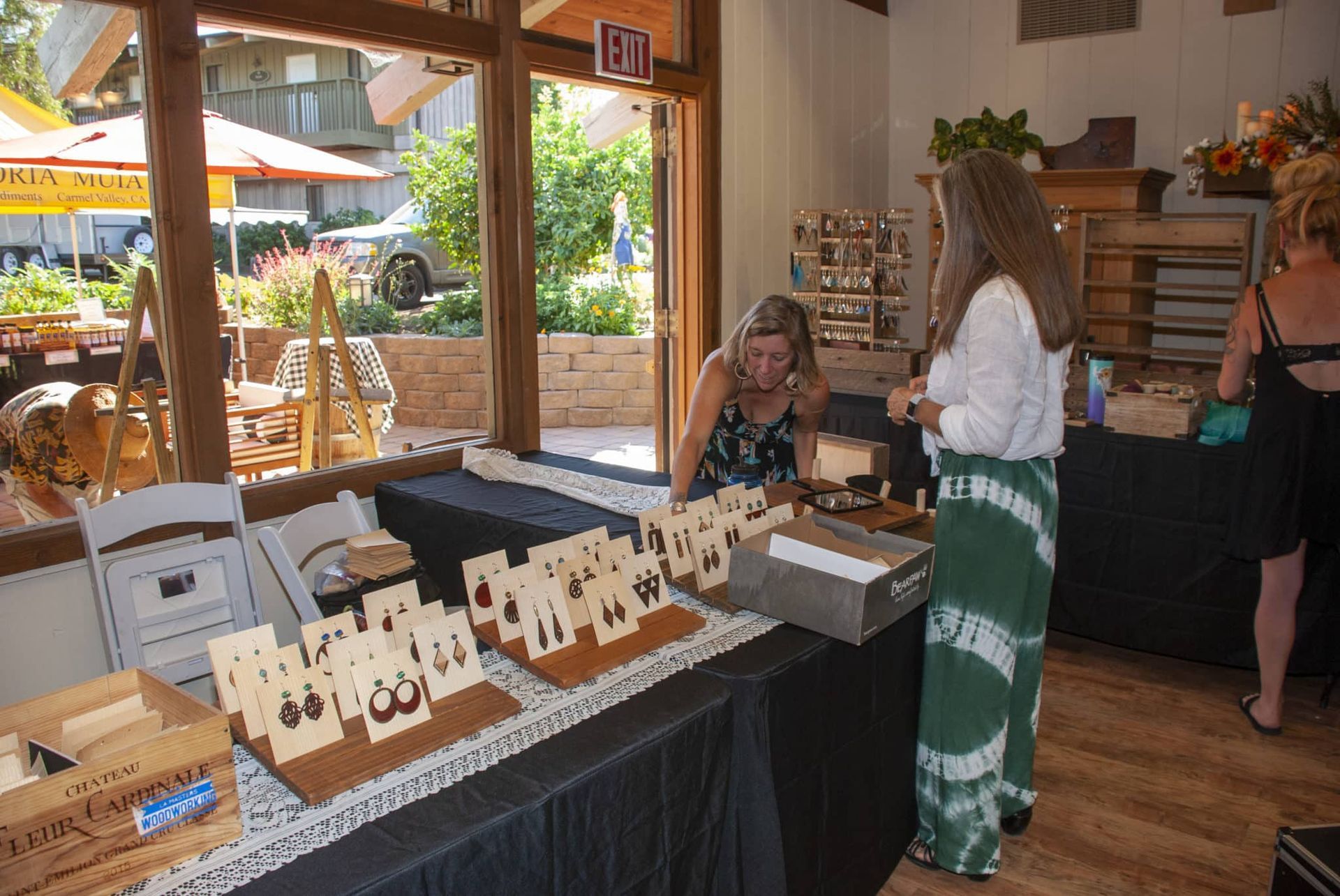 A woman is standing in front of a table with earrings on it.