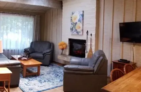 A living room with a fireplace , couch , chair , table and television.