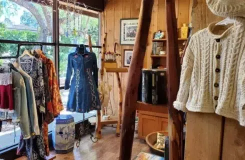 A store filled with clothes and a sweater on a mannequin.