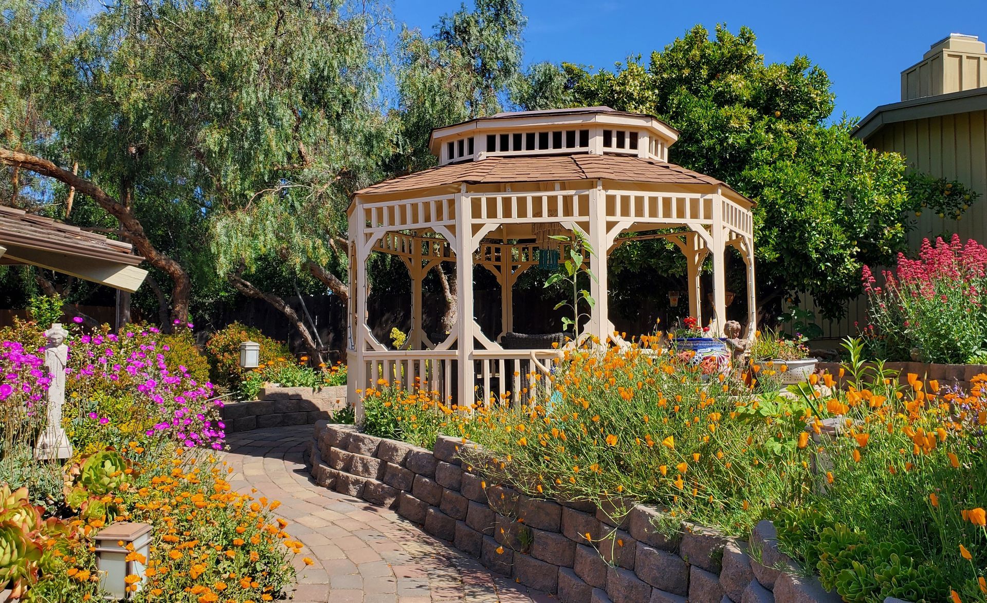 A gazebo is surrounded by flowers and trees in a garden