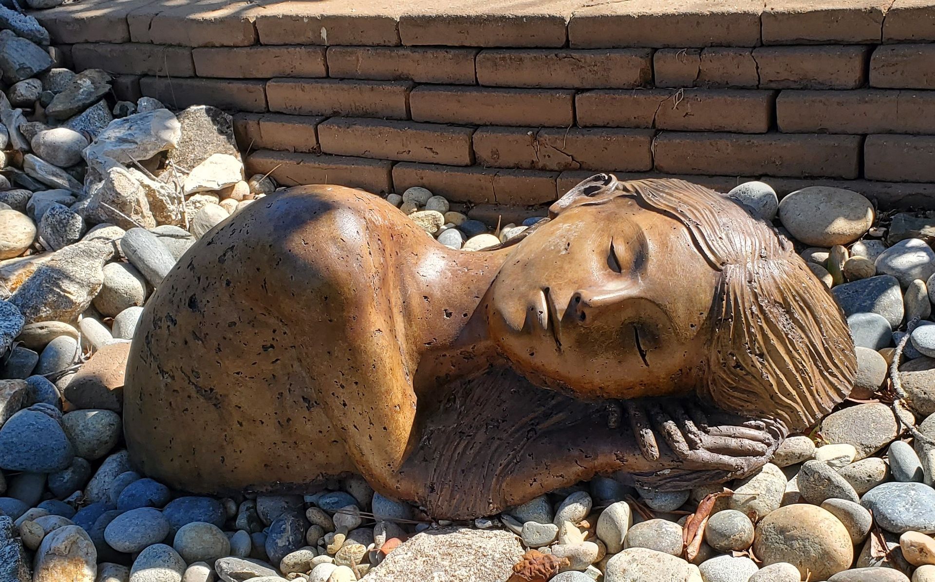 A statue of a woman laying on a pile of rocks