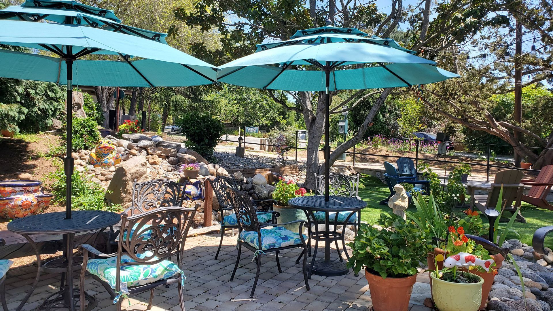 A patio with tables and chairs and umbrellas in a garden.