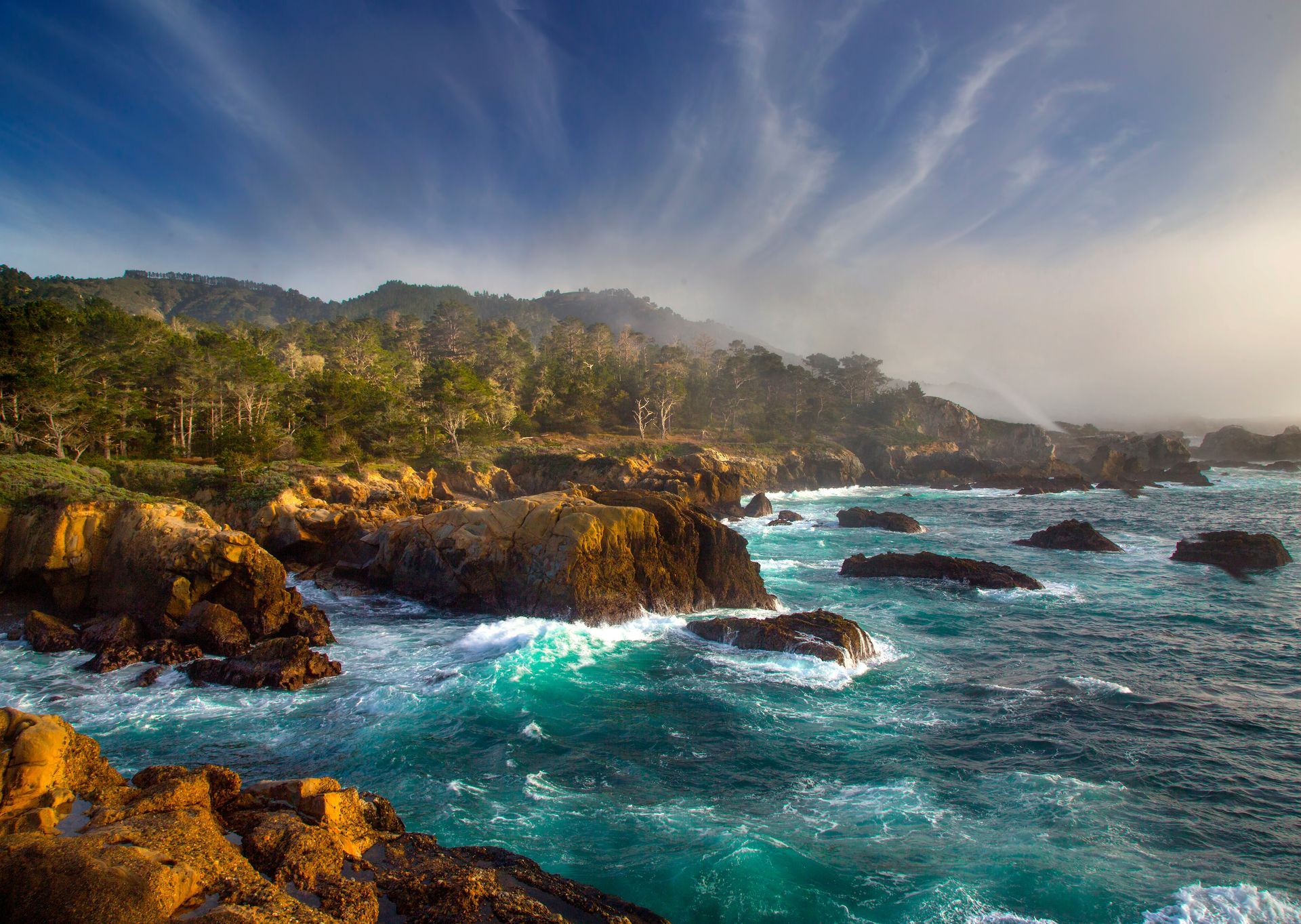 A cliff overlooking a body of water with mountains in the background