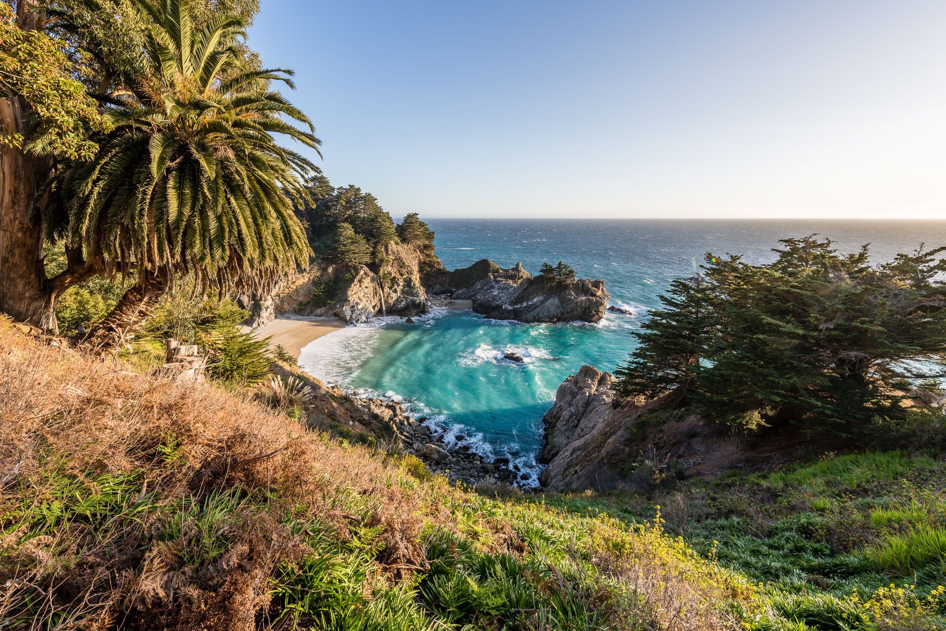 A view of a beach from a cliff overlooking the ocean.