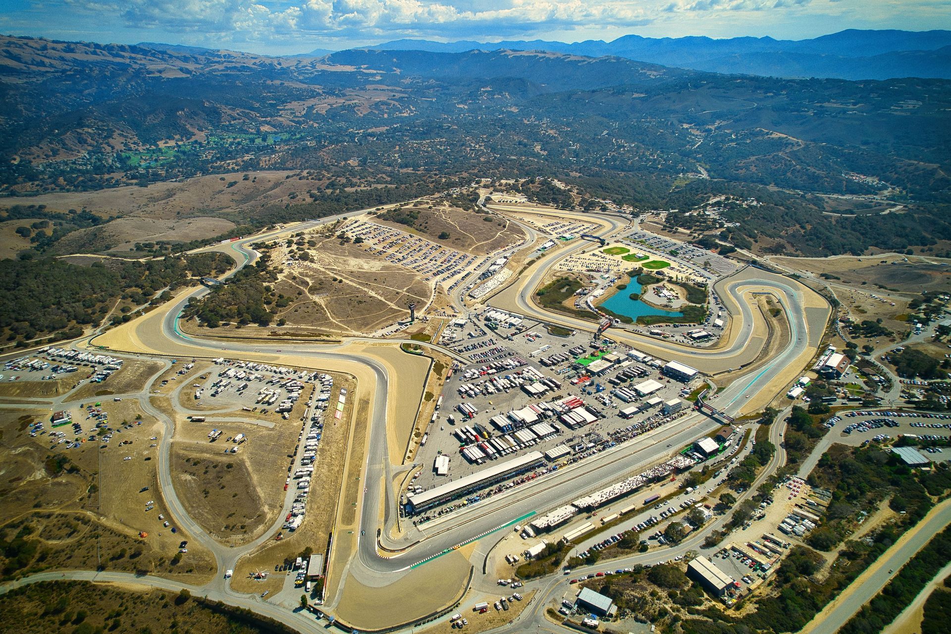 Aerial view of Laguna Seca Raceway, a racetrack winding through a hillside landscape.