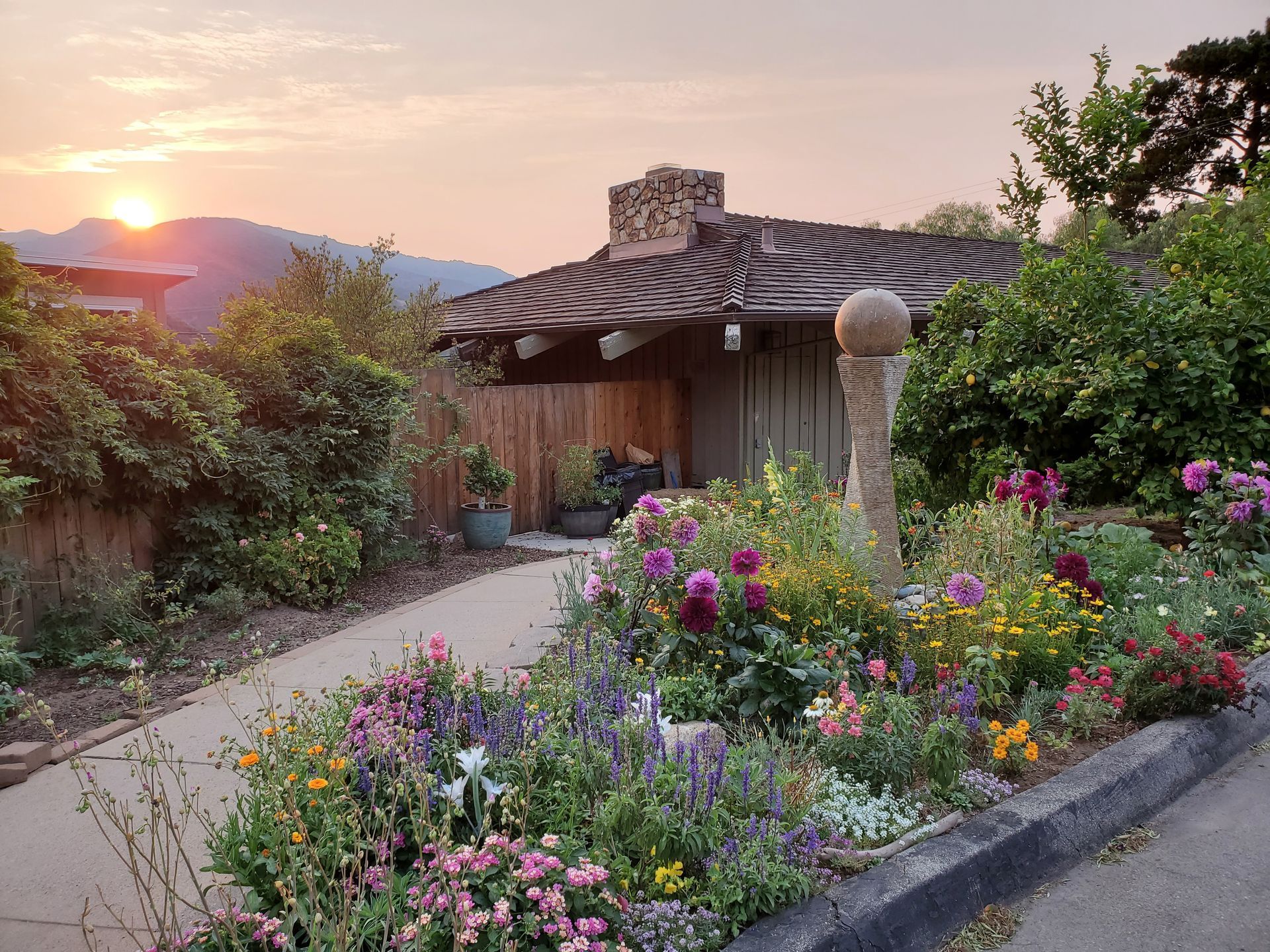 A house with flowers in front of it and a sunset in the background