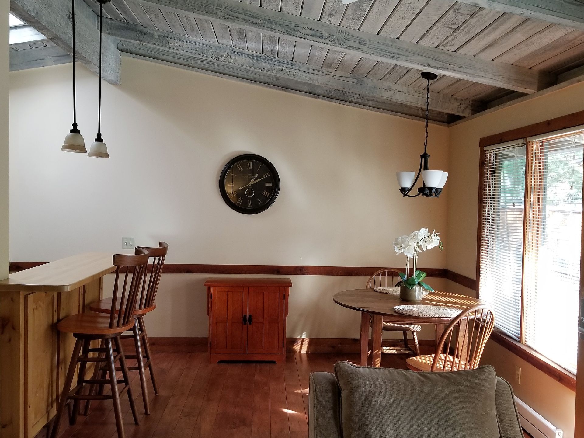 A living room with a table and chairs and a clock on the wall.