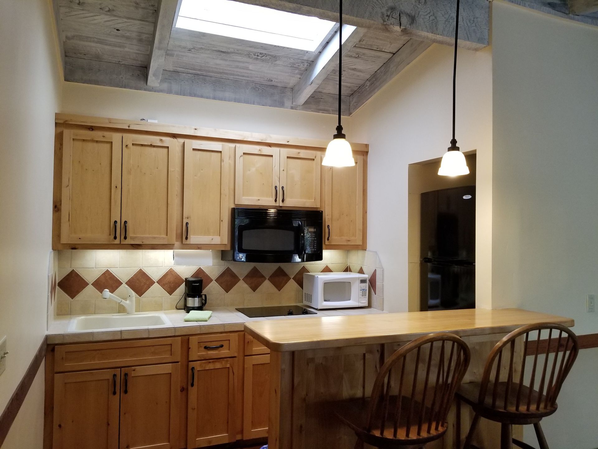 A kitchen with wooden cabinets and a microwave