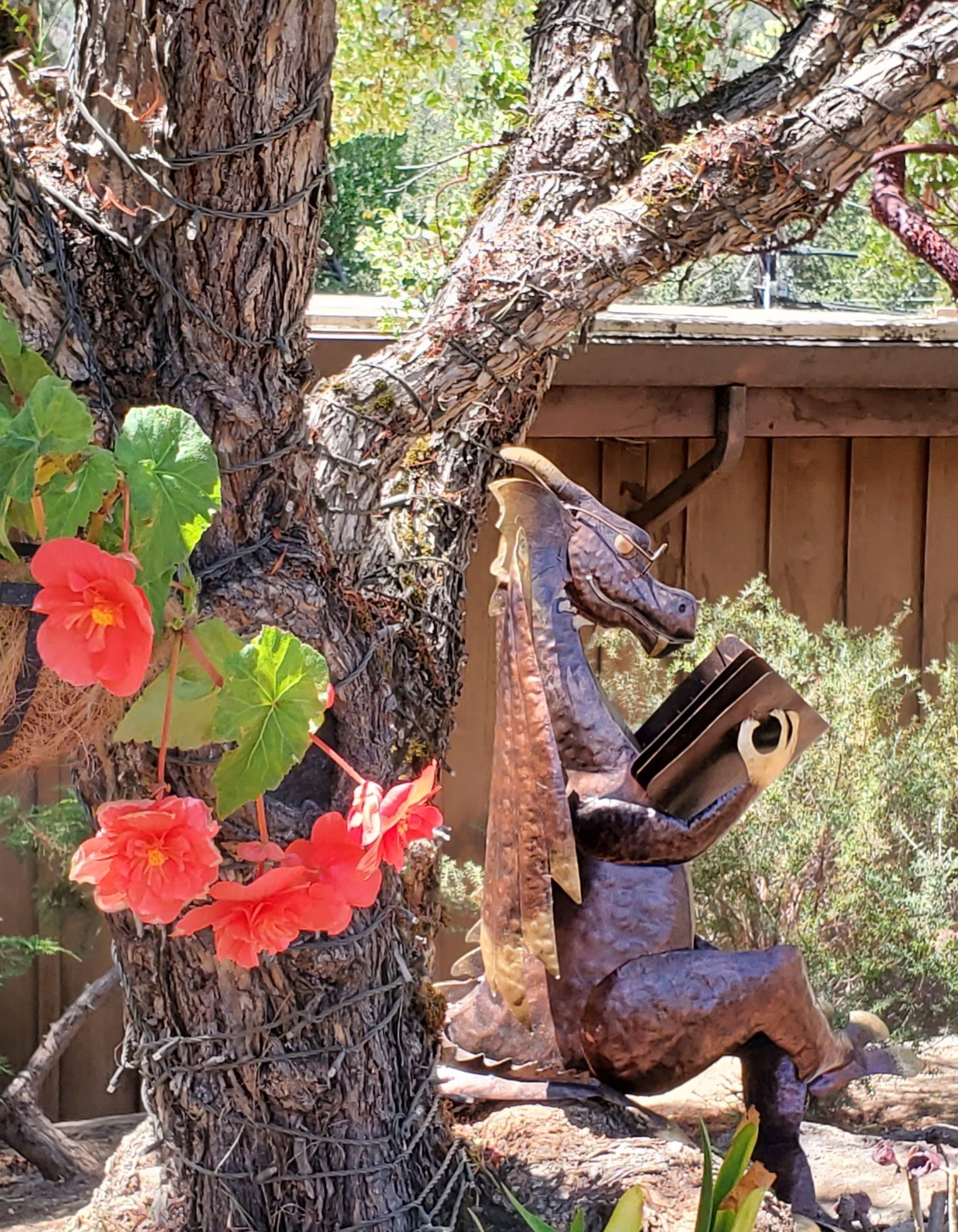 A statue of a man sitting under a tree holding a book.