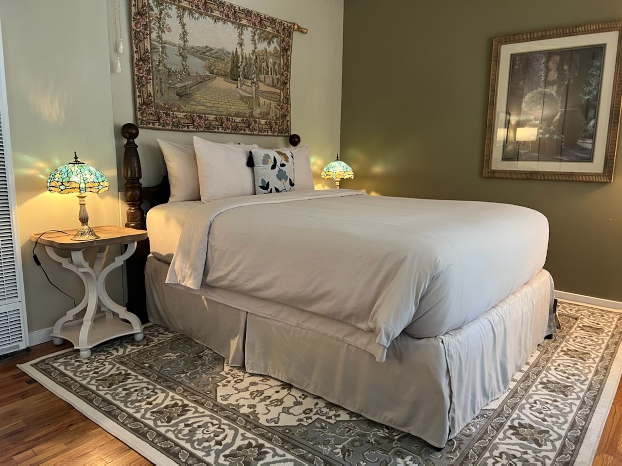 A bedroom with a bed , nightstand , rug and lamps.