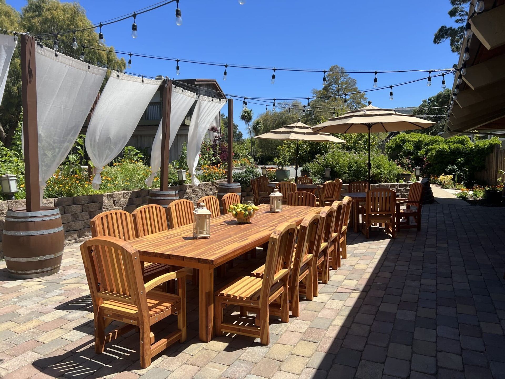 A long wooden table and chairs are sitting on a patio.