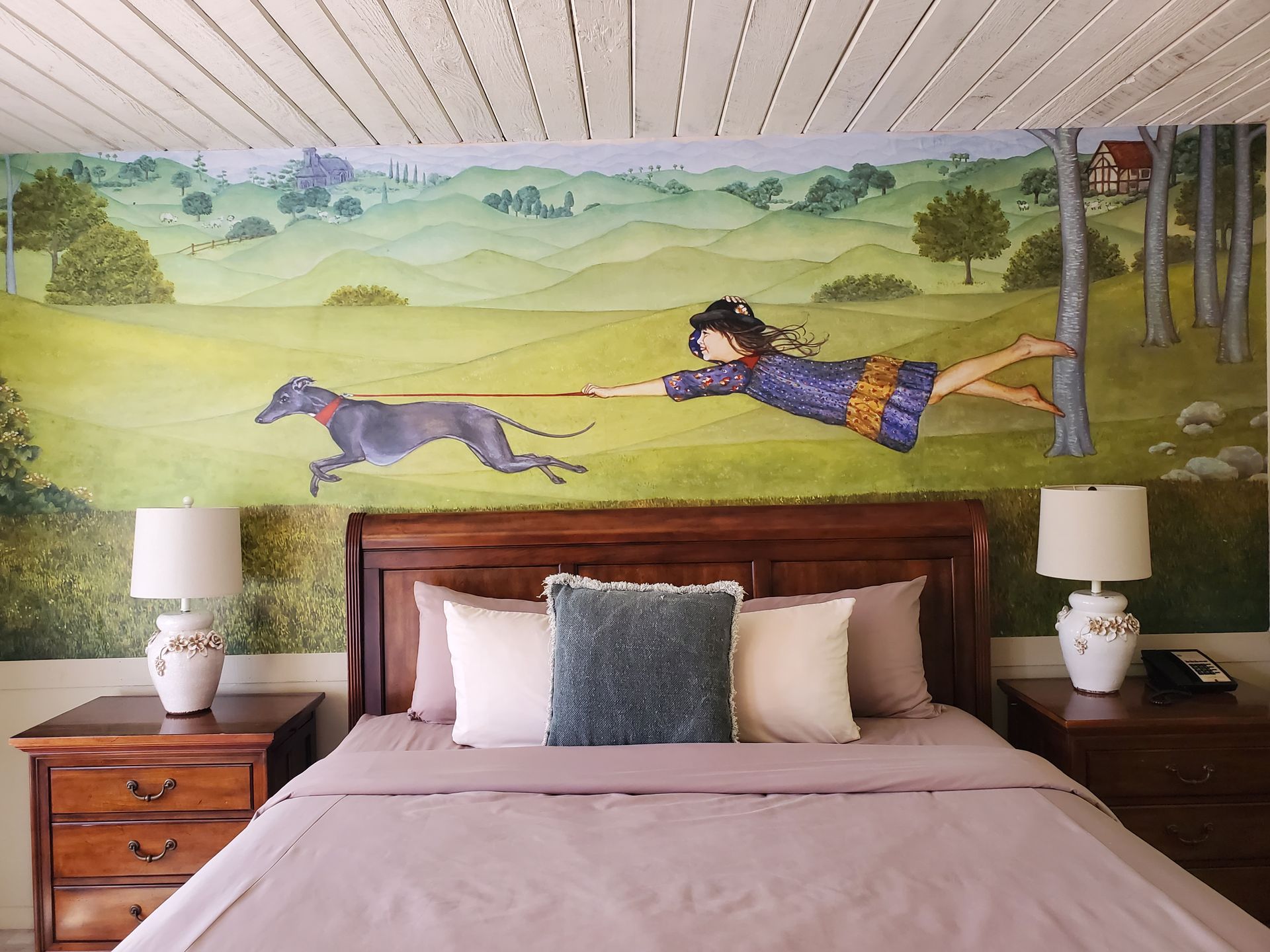 A bedroom with a painting of a girl pulling a dog on a leash