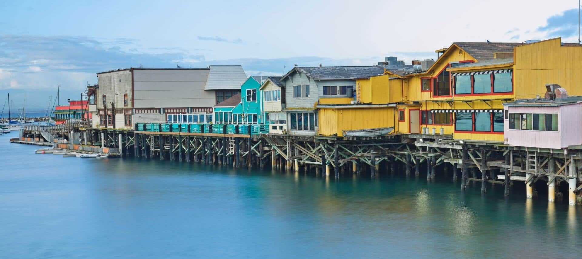 A row of colorful houses on stilts overlooking a body of water.