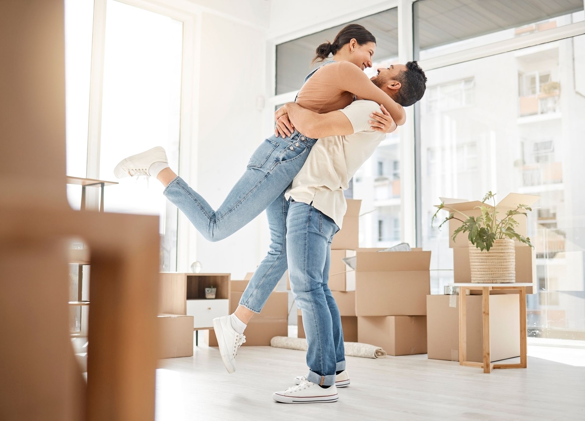 A man is holding a woman in his arms in a room filled with cardboard boxes.