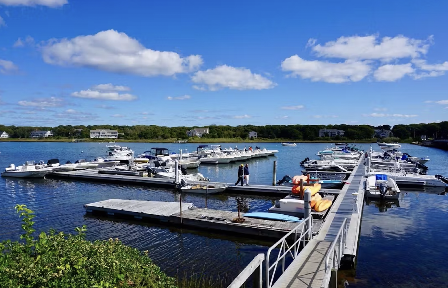 A marina filled with boats and jet skis on a sunny day.