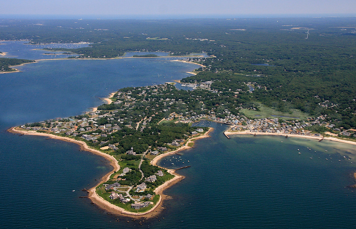 An aerial view of a small island in the middle of a large body of water surrounded by trees.