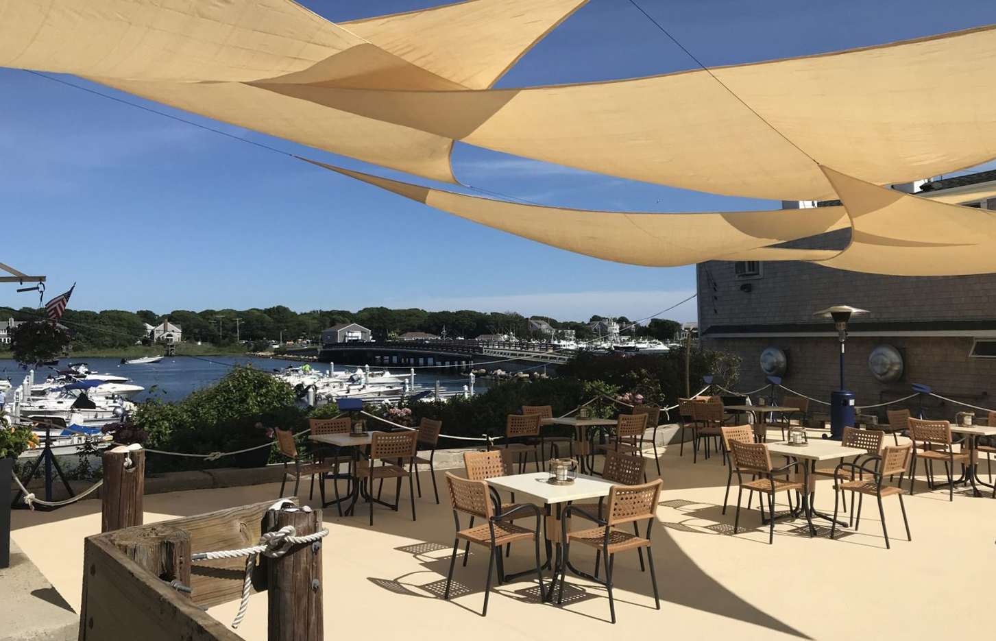 A patio with tables and chairs under umbrellas overlooking a body of water.