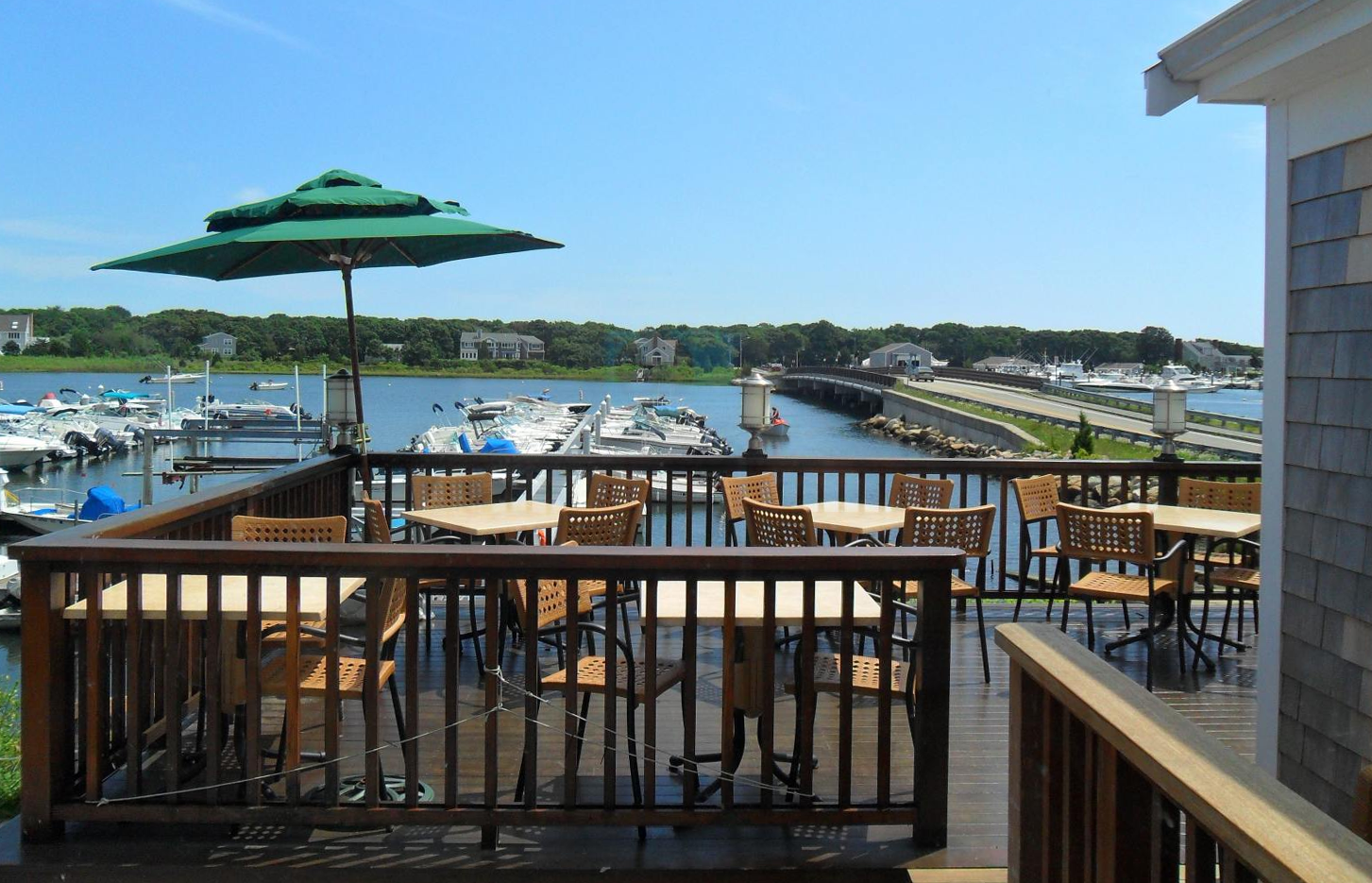 A deck with tables and chairs and an umbrella overlooking a body of water