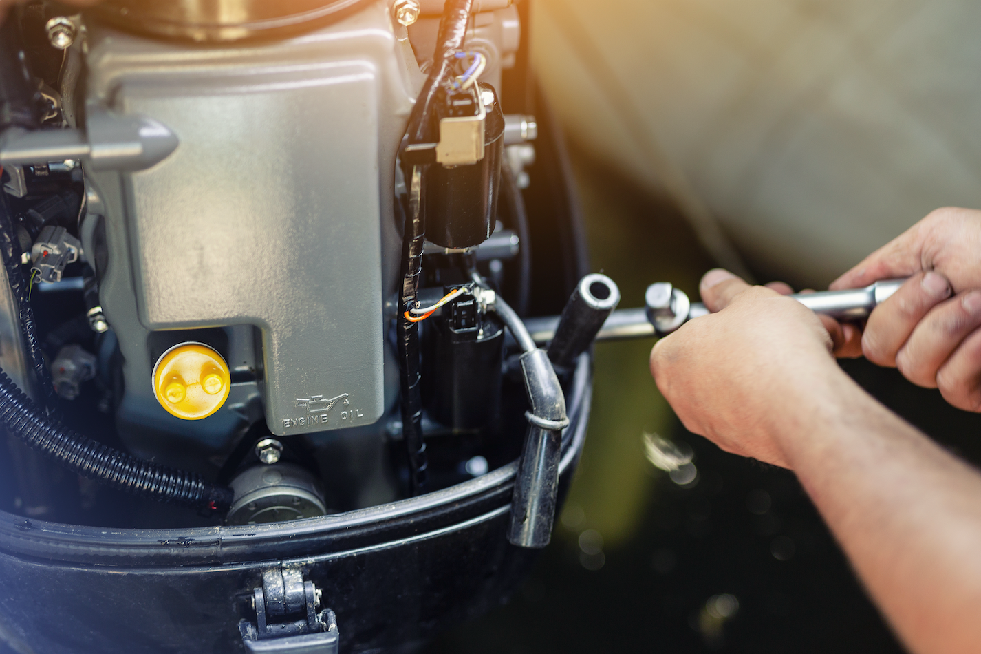 A person is working on a boat engine with a wrench.