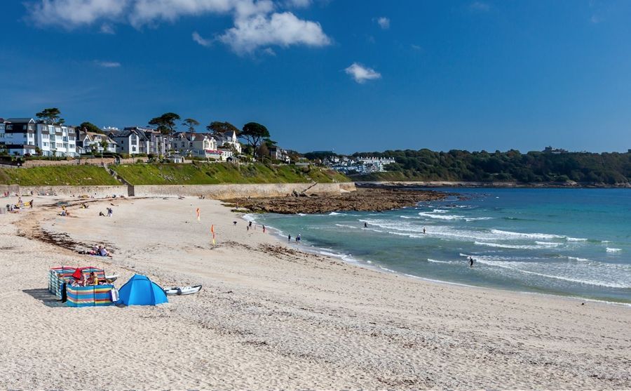 A beach with a blue tent on the sand and a blue sky in the background.
