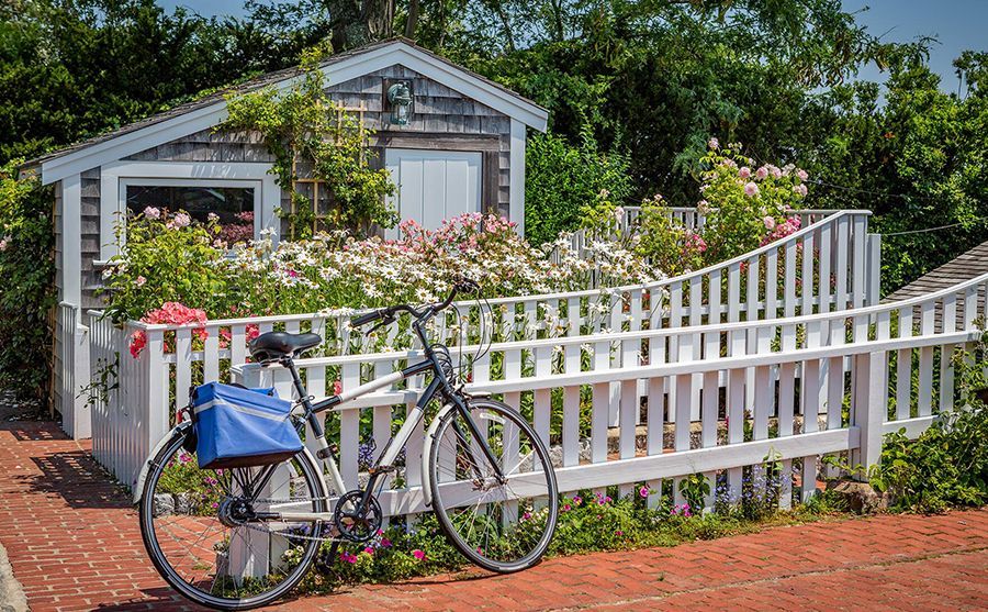 A bicycle is parked in front of a white picket fence.