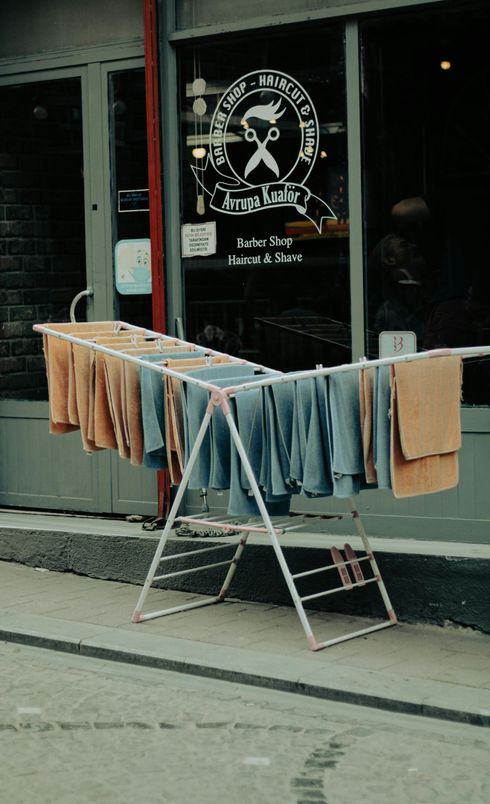 Clothes are hanging on a clothes line outside of a barber shop.