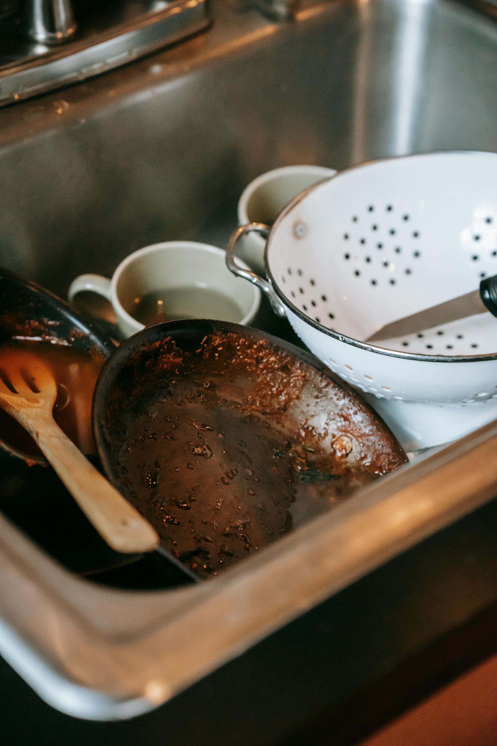 A kitchen sink filled with dirty dishes and utensils.
