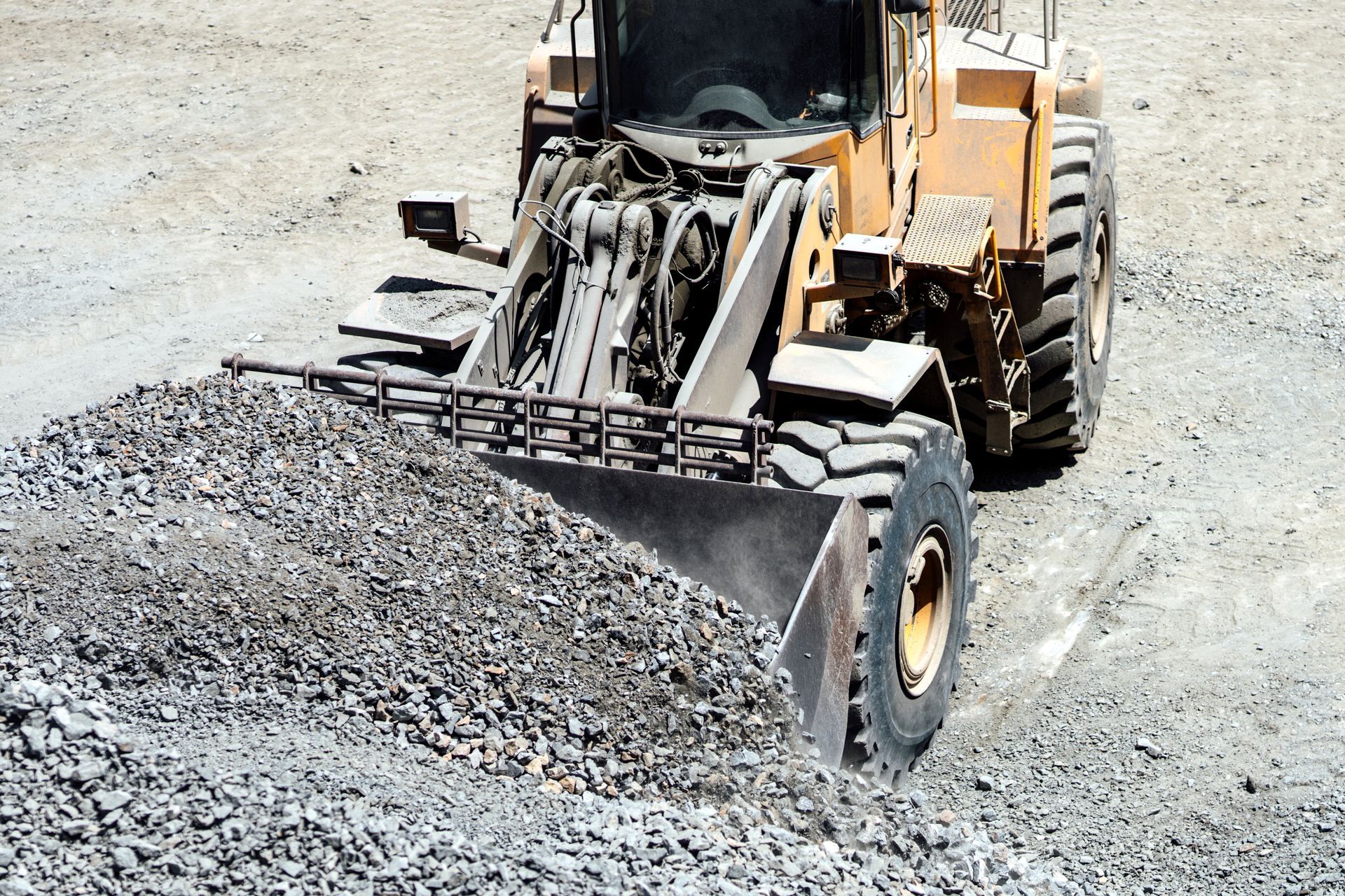 Heavy duty large wheel loader loading gravel at work site.