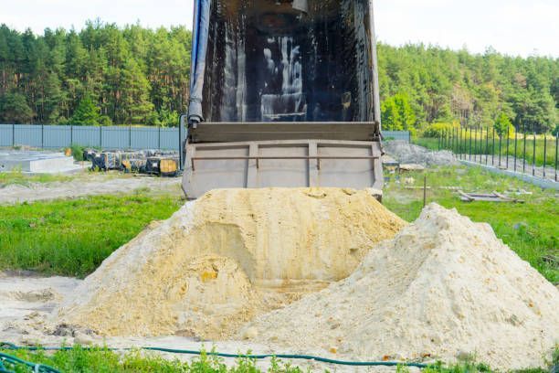 A dump truck unloads the sand.
