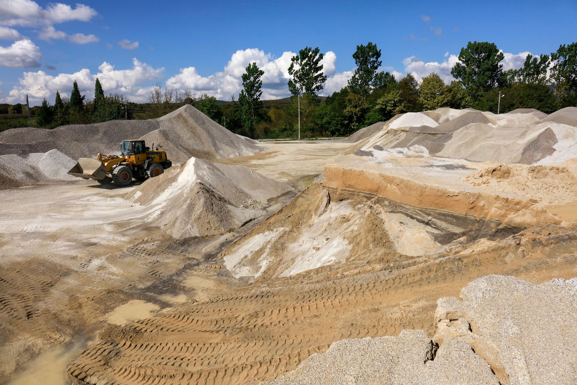 Heavy equipment machine wheel loader on a construction jobsite full of sand supply Heavy equipment machine wheel loader on a construction jobsite full of sand supply