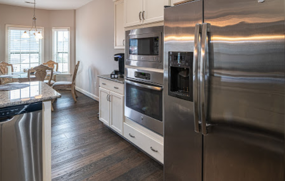 A kitchen with stainless steel appliances , a refrigerator and a microwave.